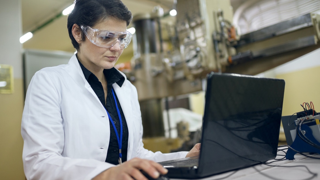 Woman in lab coat working on laptop