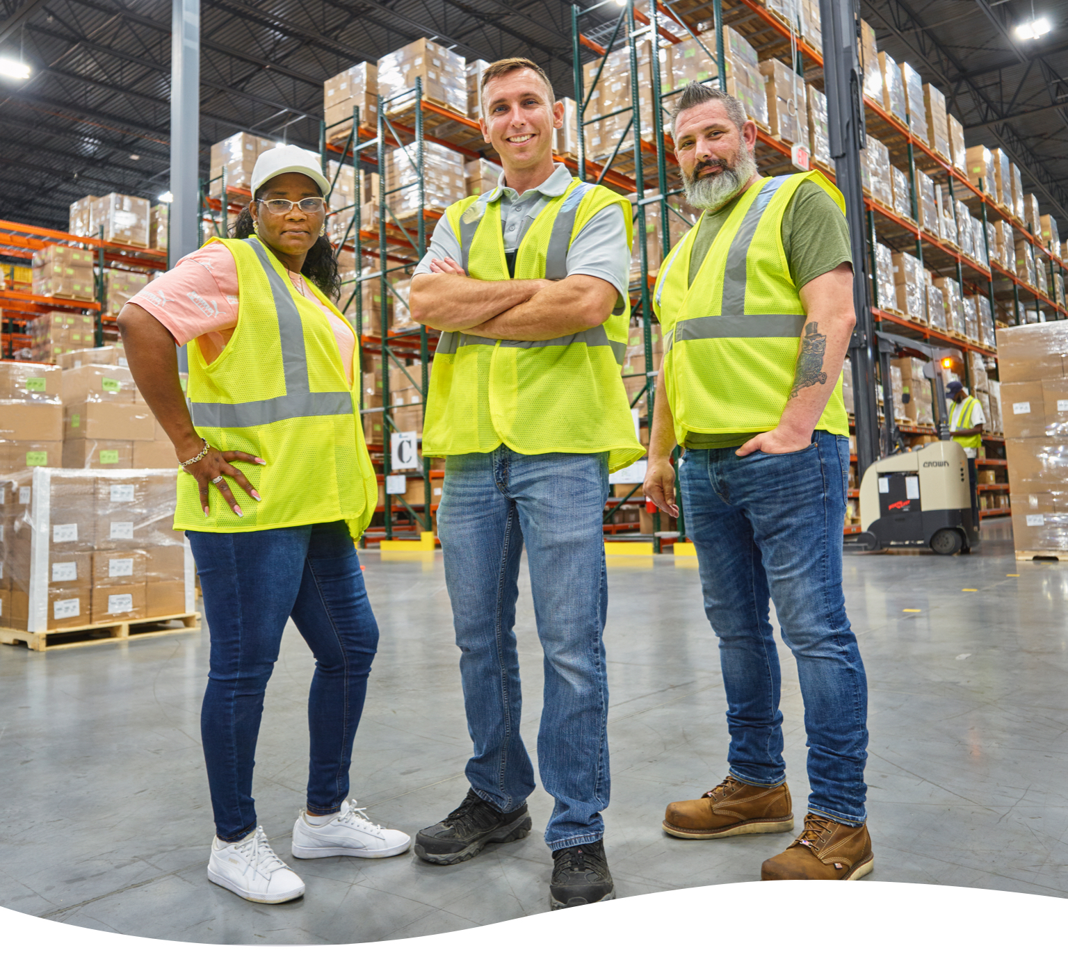 three warehouse workers in green vests