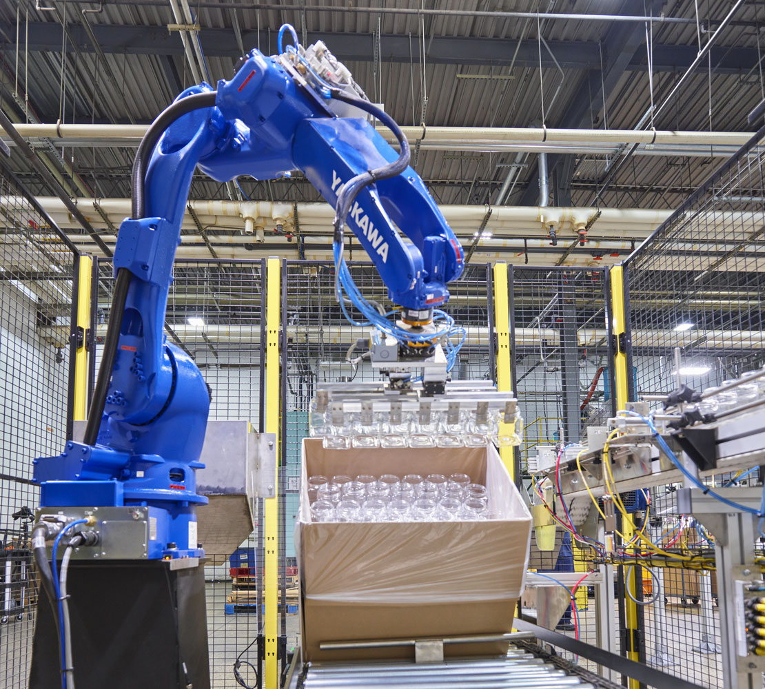 robotic arm moving box of manufactured plastic bottles off of the assembly line